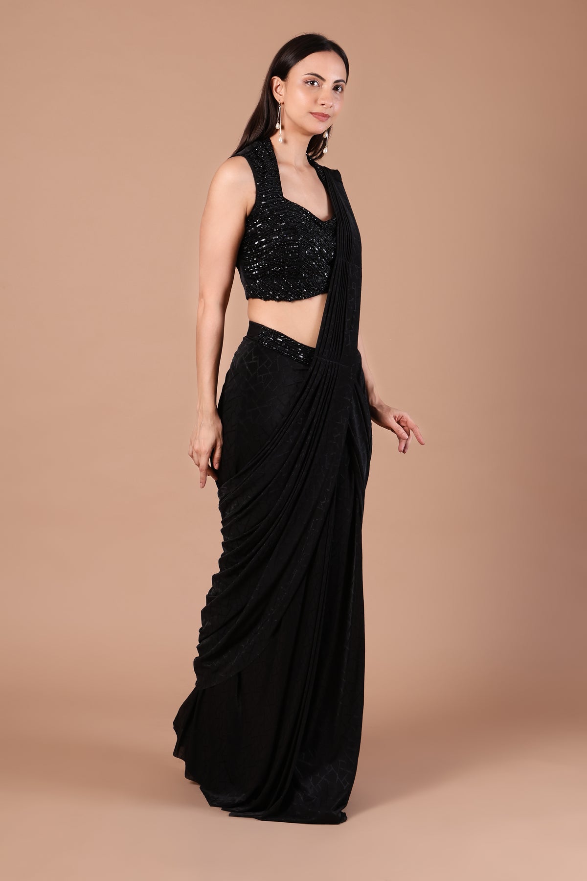 Front angled view of midnight black draped saree styled with embellished sleeveless blouse
